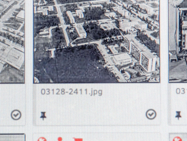 A pixelated screenshot of an interface, focused on an image, which is partially out of the frame, whose name is "03128-2411.jpg". Under the name, there is the logo of a pin in a rounded, checked box. The image is quite blurry, but it seems like an aerial picture of a complex with some buildings.